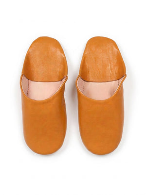 Paire de babouches marocaines en cuir moutarde sur fond blanc, vue de dessus