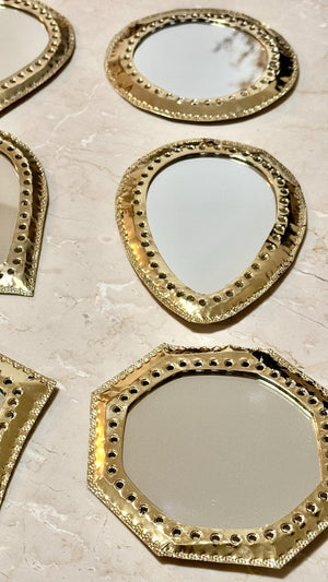 Collection de miroirs marocains en laiton martelé, formes ronde, octogonale et goutte, posés sur marbre beige