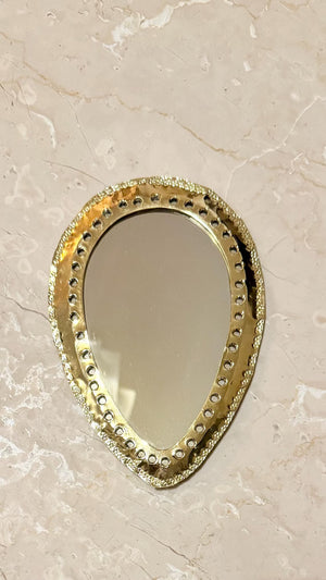 Miroir marocain ovale en goutte, cadre laiton martelé, accroché sur mur en marbre