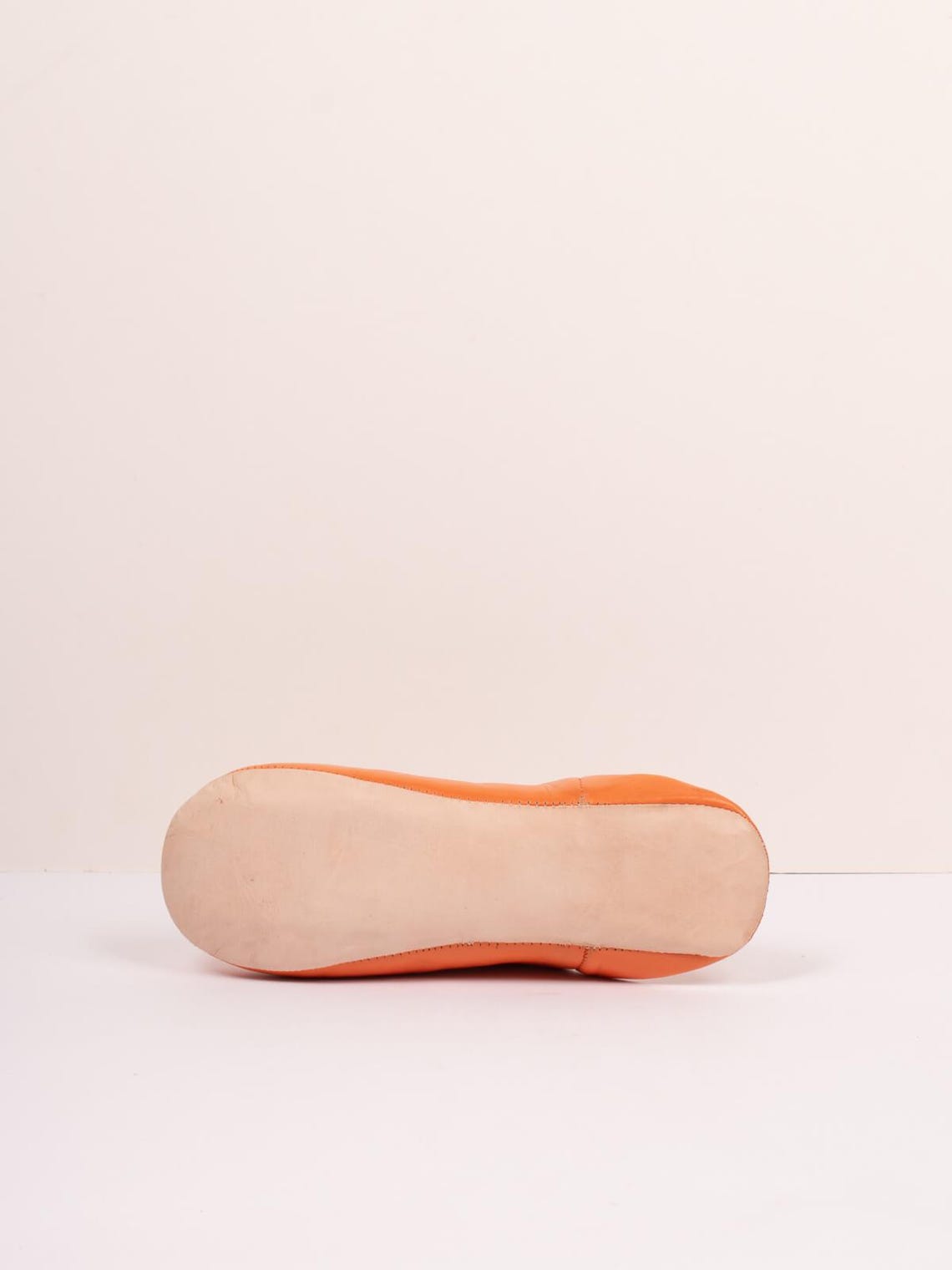 Semelle en cuir naturel d'une babouche marocaine orange, vue de profil sur fond clair