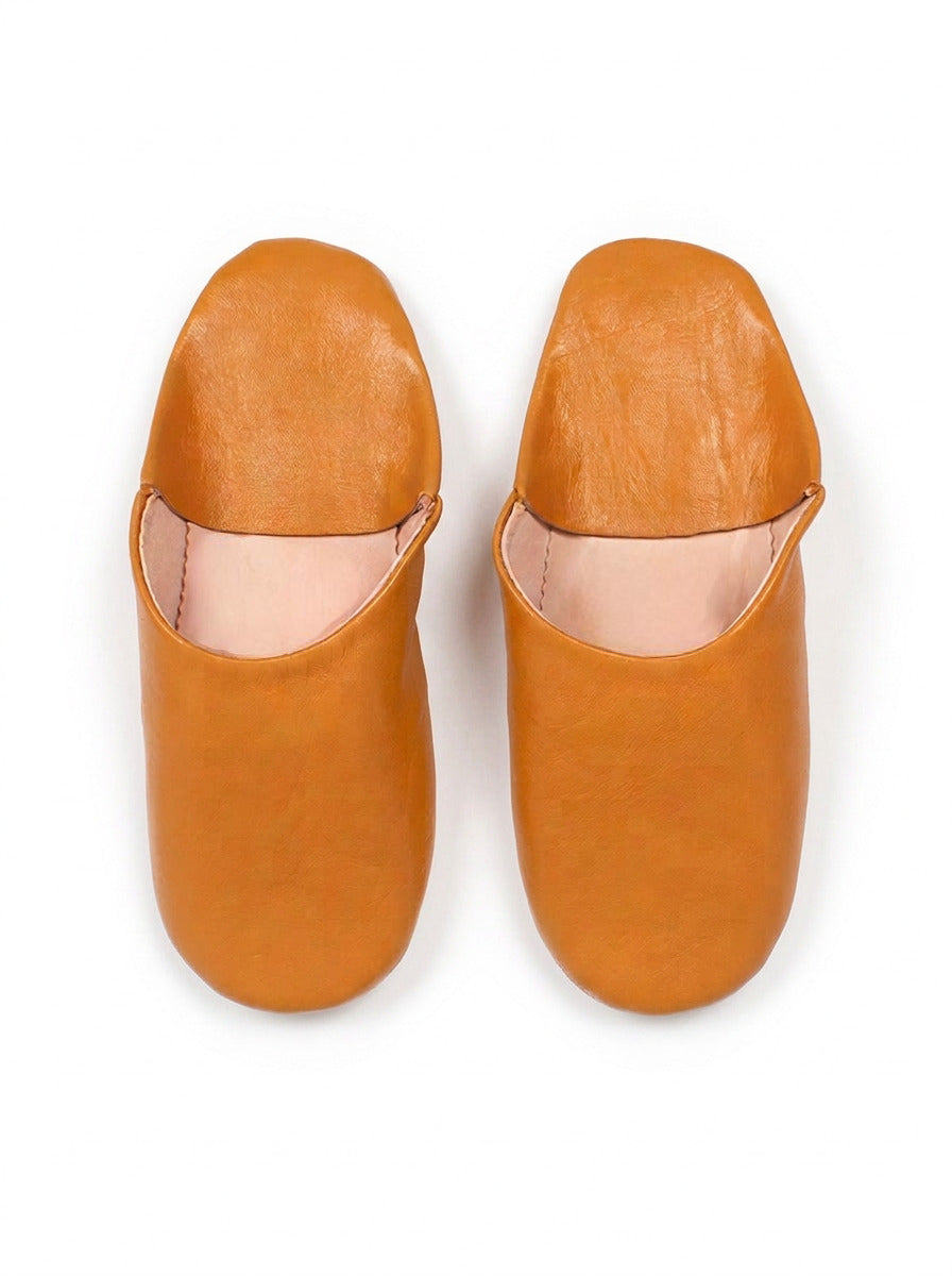 Paire de babouches marocaines en cuir moutarde sur fond blanc, vue de dessus