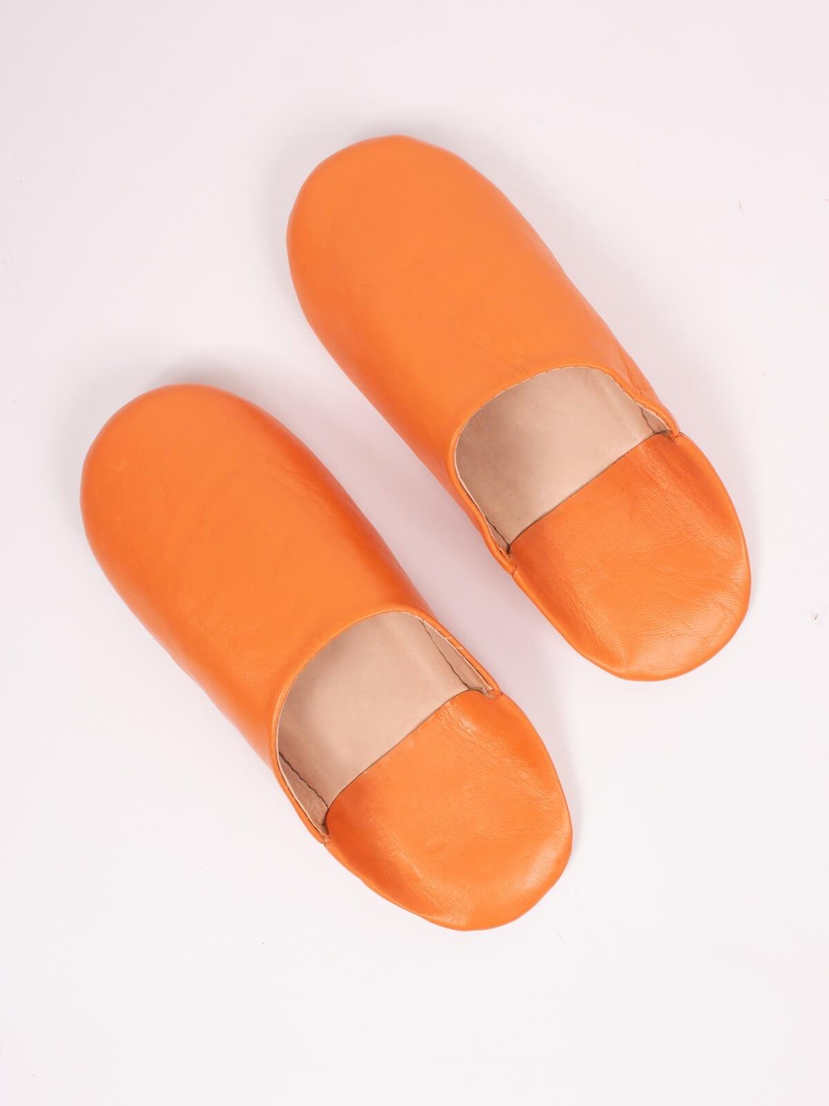 Paire de babouches marocaines en cuir orange sur fond blanc, vue de dessus