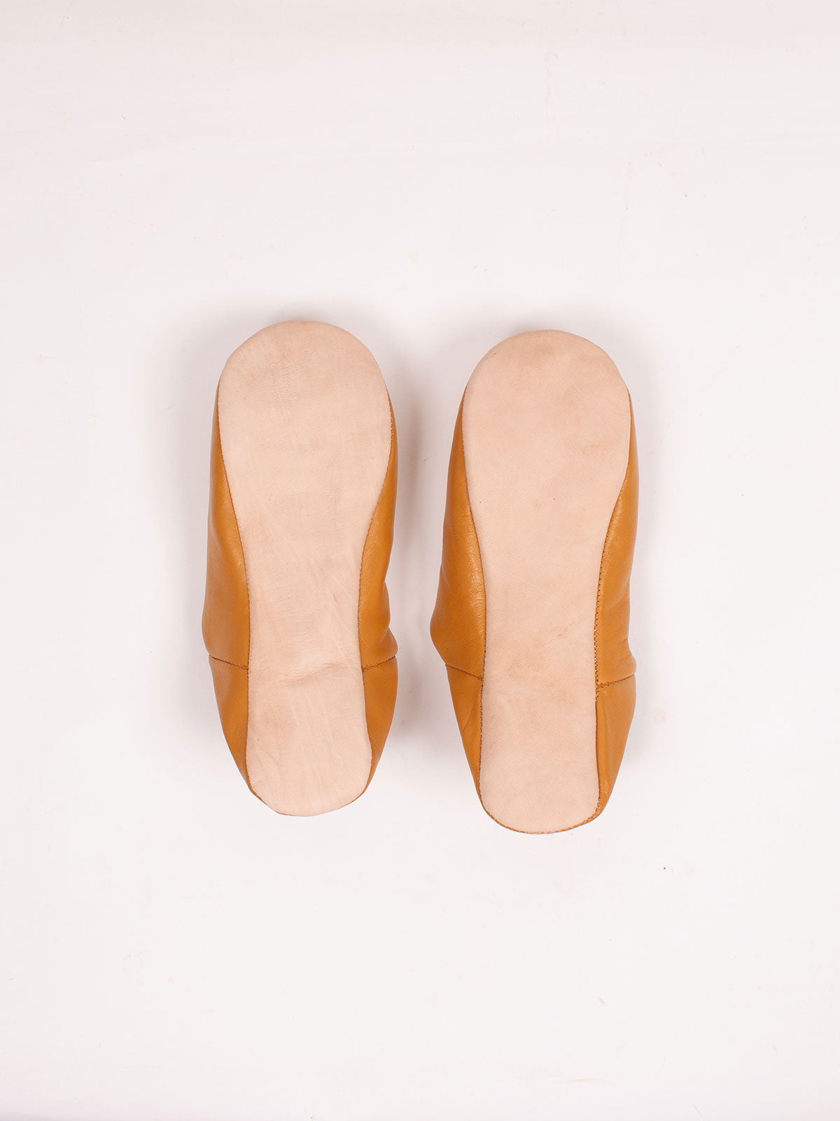 Semelles en cuir naturel d'une paire de babouches marocaines moutarde, vue de dessous
