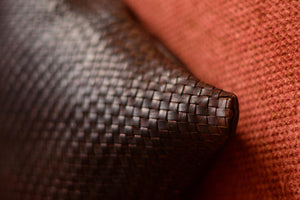 Coussin artisanal en cuir véritable tressé, fauteuil rouille et décor en bois brut