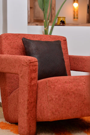 Gros plan sur le coin d'un coussin en cuir tressé, finition artisanale et reflets du cuir