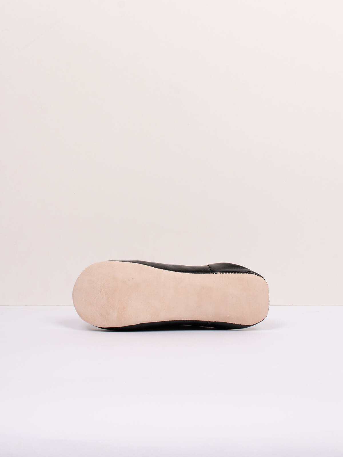 Semelle en cuir naturel d'une babouche marocaine noir, vue de profil sur fond clair