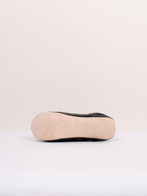 Semelle en cuir naturel d'une babouche marocaine noir, vue de profil sur fond clair